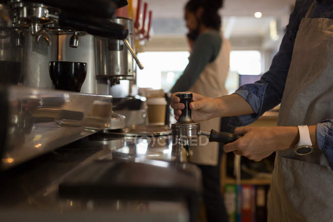Mid section of waitress preparing coffee at coffee machine in cafe — Stock Photo