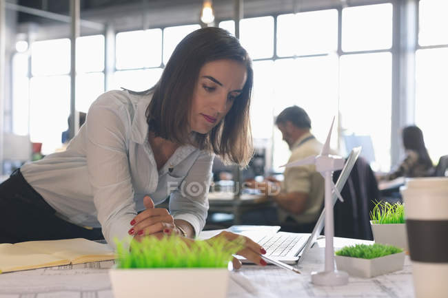 Женщина-руководитель смотрит на модель ветряной мельницы в офисе — стоковое фото