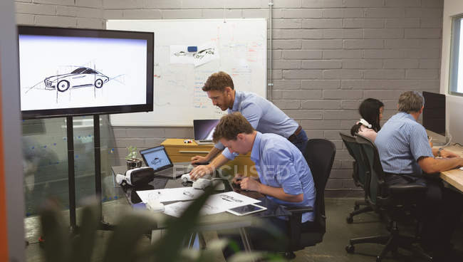 Бізнес-колеги обговорюють модель автомобіля в офісі — стокове фото