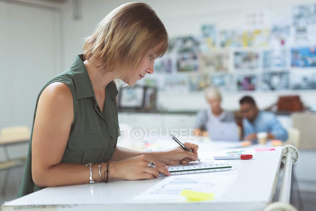 Side view of female executive working on drafting table in office — Stock Photo