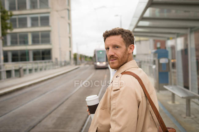 Hombre tomando café en la plataforma en la estación de tren - foto de stock
