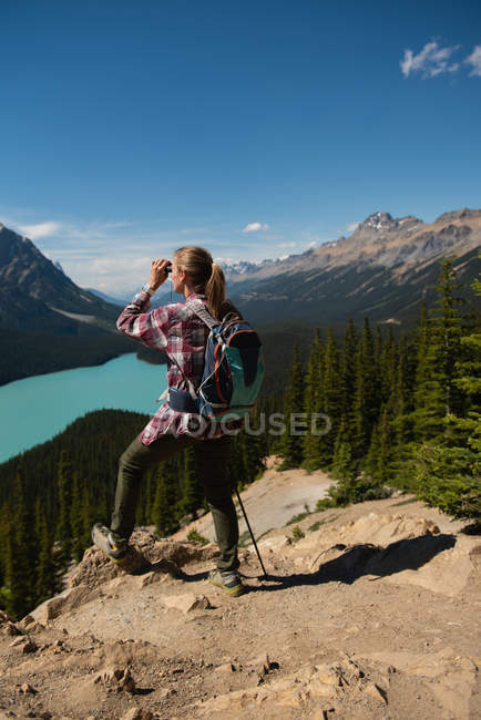 Wanderin blickt an einem sonnigen Tag durch ein Fernglas auf die Landschaft — Stockfoto