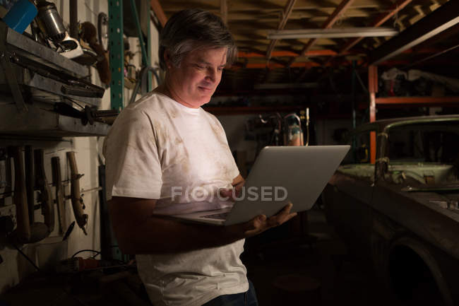 Male mechanic using laptop in garage — Stock Photo