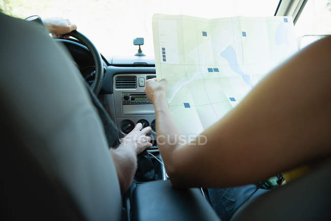 Mid section of couple looking at map while travelling in car — Stock Photo