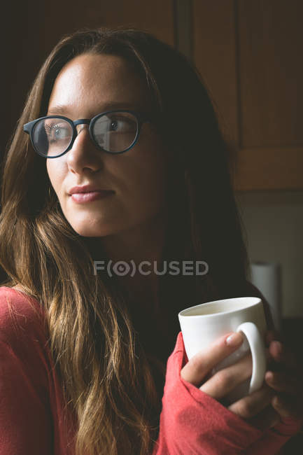 Femme réfléchie prenant un café dans la cuisine à la maison — Photo de stock