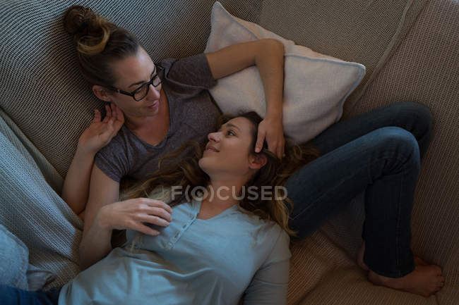 Лесбийская пара лежит на диване в гостиной дома — стоковое фото