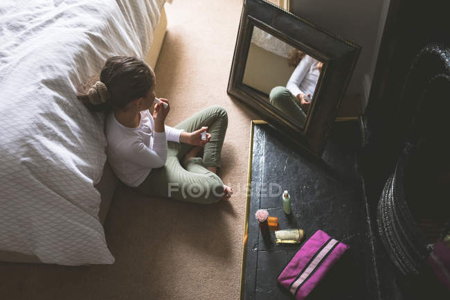 Overhead de niña aplicando lápiz labial delante del espejo en casa - foto de stock