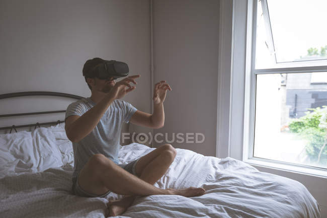 Людина за допомогою віртуальної реальності гарнітуру в спальні в домашніх умовах — стокове фото
