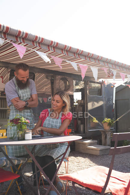 Пара рабочих возле фургона с едой в солнечный день — стоковое фото