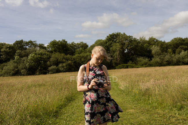 Femme tenant un appareil photo numérique sur le terrain à la campagne — Photo de stock