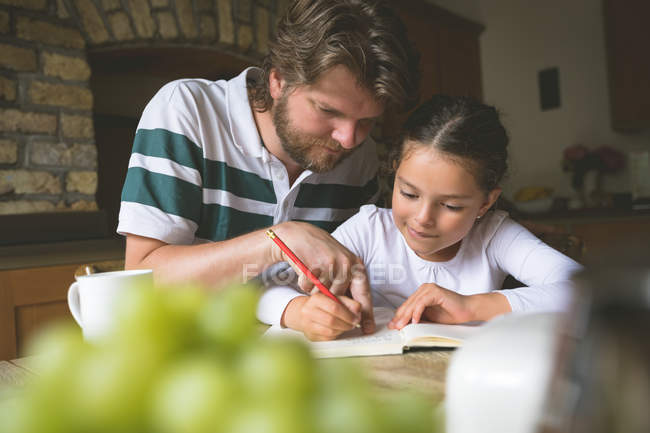 Отец помогает дочери в учебе на дому — стоковое фото