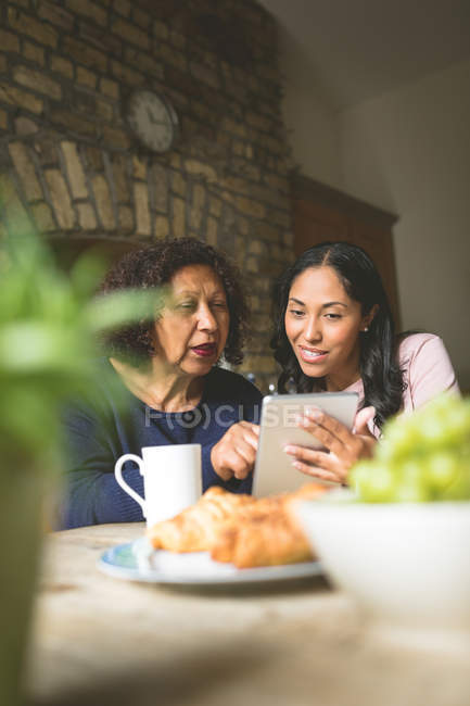 Mother and daughter using digital tablet at home — Stock Photo