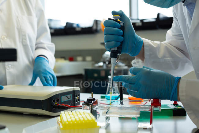 Sección media de científicos experimentando en laboratorio - foto de stock