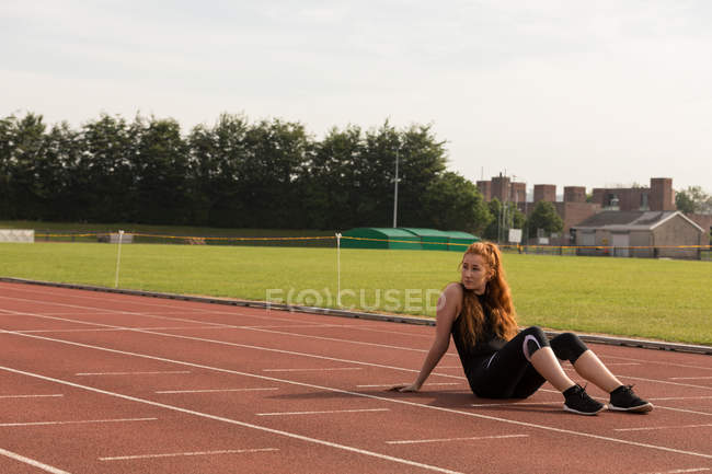 Jovem atlética relaxante feminino em uma pista de corrida — Fotografia de Stock