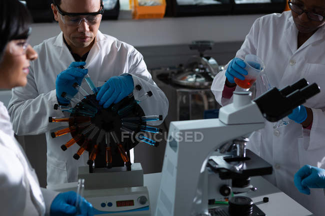 Equipo de científicos experimentando juntos en laboratorio - foto de stock