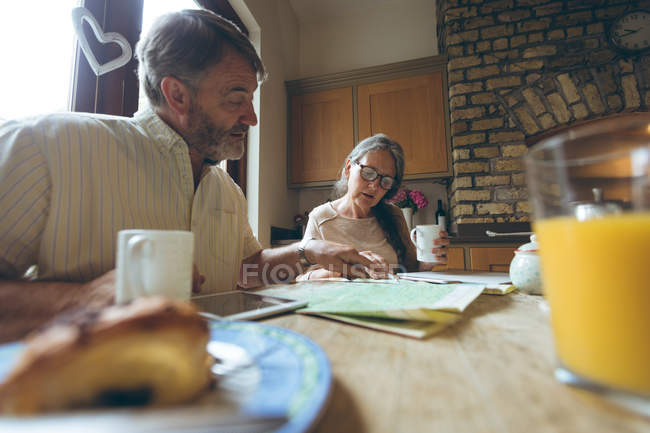 Seniorenpaar diskutiert zu Hause über eine Landkarte — Stockfoto