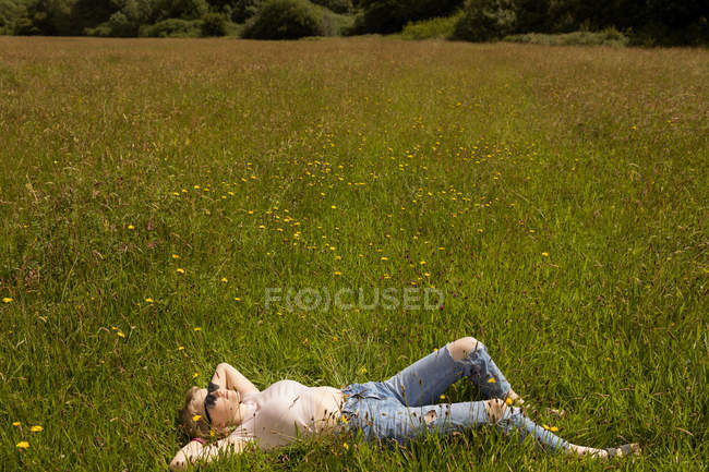 Jeune femme relaxante sur le terrain — Photo de stock