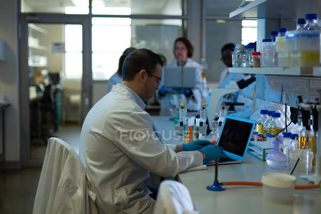 Cientista masculino atento usando laptop em laboratório — Fotografia de Stock