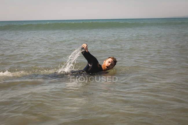 Surfista nadando en el mar en un día soleado - foto de stock