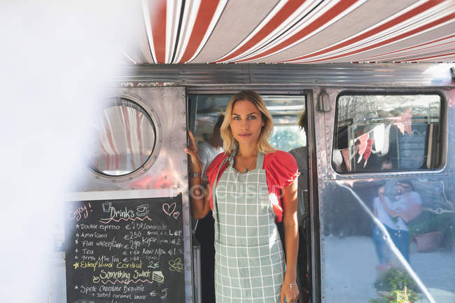 Beautiful female waitress standing in food truck — Stock Photo