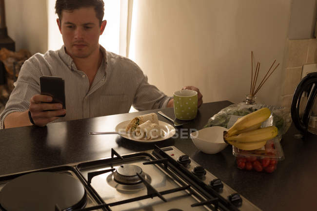 Homem com deficiência usando telefone celular na mesa de jantar em casa — Fotografia de Stock