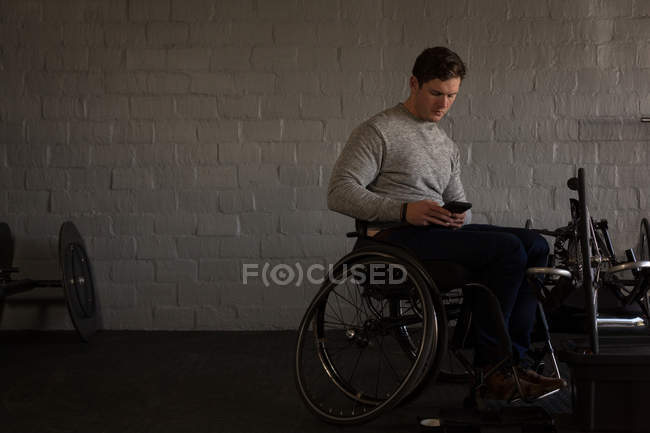 Молодой инвалид с помощью мобильного телефона в мастерской — стоковое фото