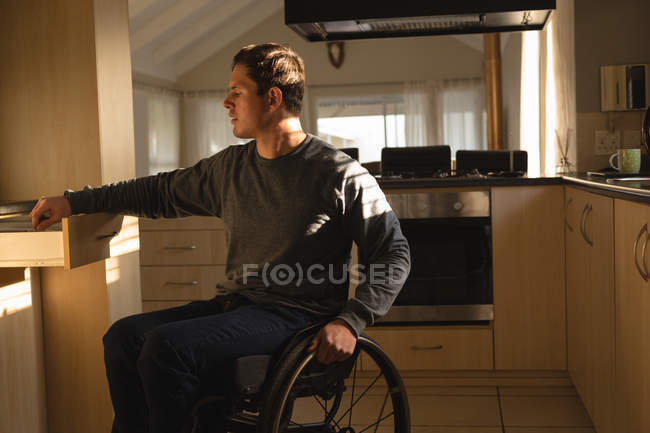 Homem com deficiência removendo utensílio na cozinha em casa — Fotografia de Stock