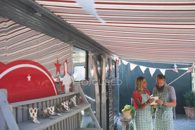 Young couple using digital tablet near food truck — Stock Photo