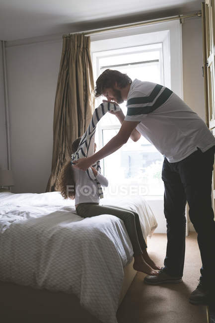 Father helping her daughter in wearing cloth at home — Stock Photo