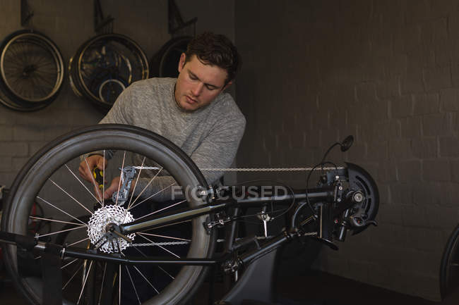 Jeune homme handicapé réparant fauteuil roulant à l'atelier — Photo de stock