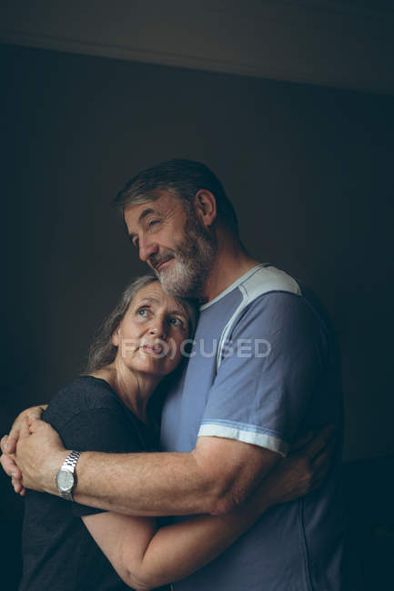 Romântico casal sênior abraçando uns aos outros em casa — Fotografia de Stock