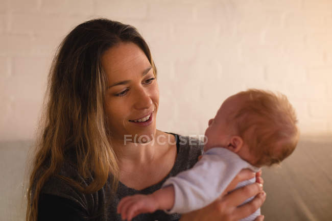 Mãe brincando com bebê no sofá em casa — Fotografia de Stock