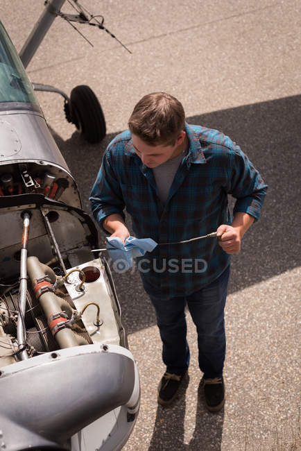 Високий кут зору інженера, що обслуговує авіаційний двигун біля ангара — стокове фото