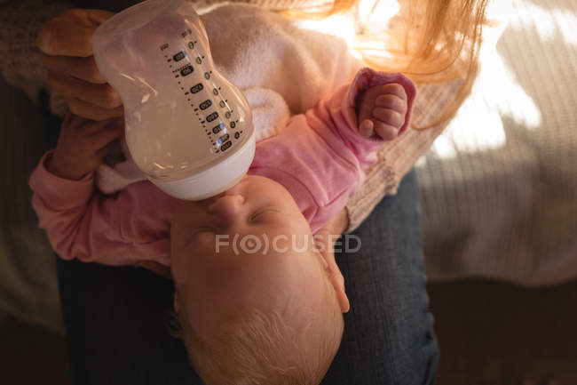 Крупним планом мати годує дитину молоком на дивані вдома — стокове фото