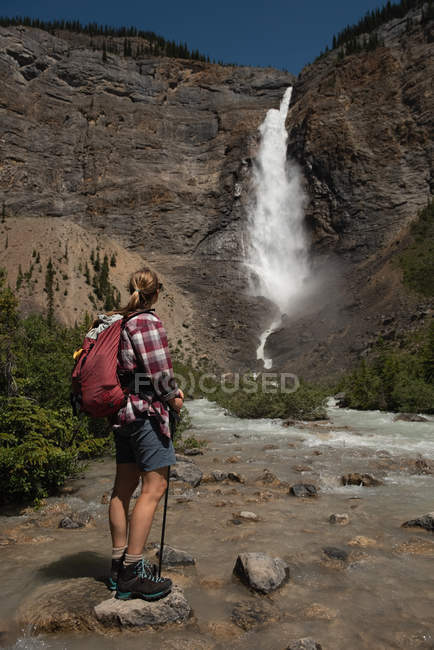 Caminhante feminina olhando para cachoeira nas montanhas — Fotografia de Stock