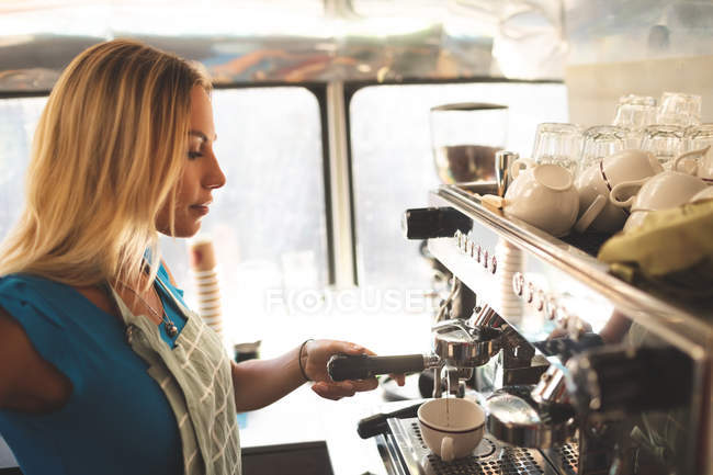 Vue latérale du serveur féminin préparant le café dans le camion de nourriture — Photo de stock