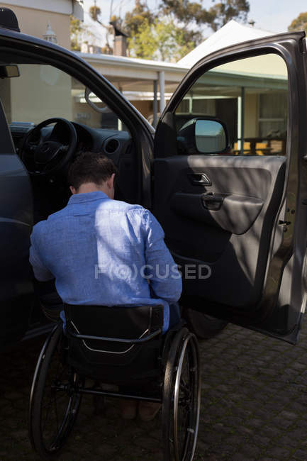 Вид ззаду інваліда в інвалідному візку біля автомобіля — стокове фото