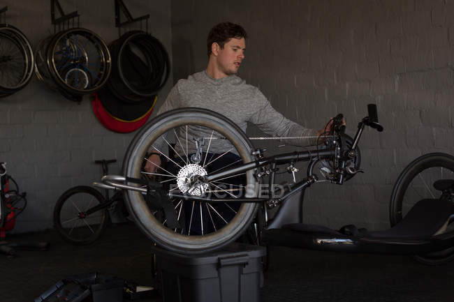 Молодий інвалідний чоловік ремонтує інвалідне крісло на майстерні — стокове фото