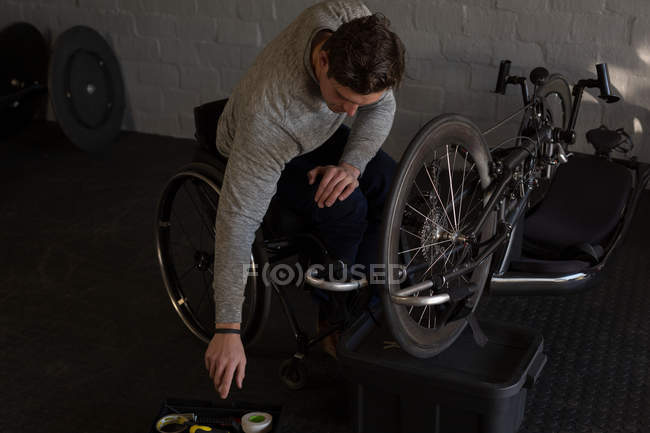 Молодой инвалид ремонтирует инвалидное кресло в мастерской — стоковое фото