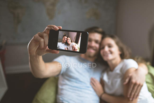 Пара, делающая селфи с мобильного телефона дома — стоковое фото