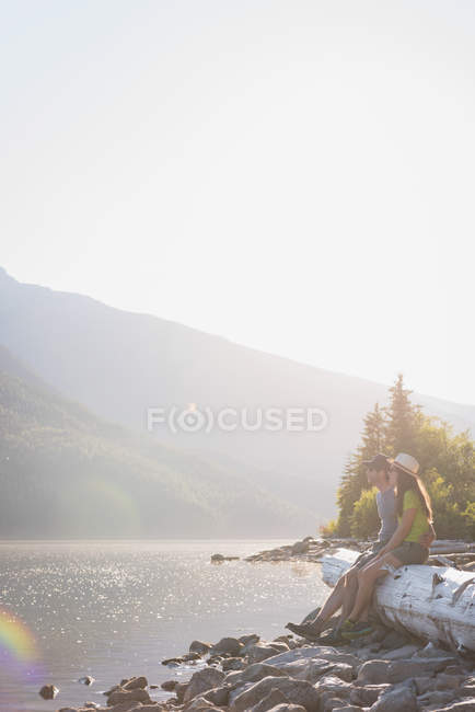 Casal relaxante em madeira log perto ribeirinha em montanhas — Fotografia de Stock
