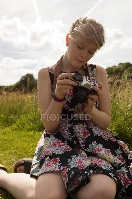 Mujer revisando fotos en la cámara en el campo - foto de stock