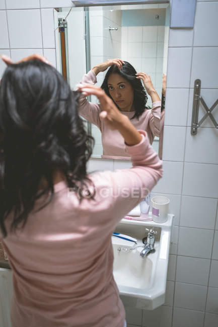 Donna in piedi con mano sui capelli in bagno a casa — Foto stock