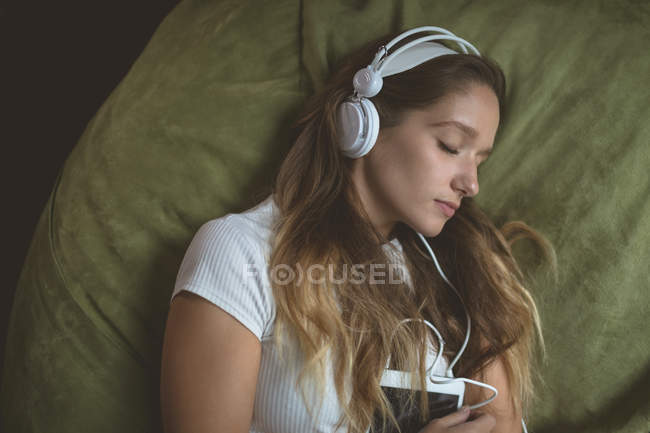Frau hört Musik über Kopfhörer während sie zu Hause schläft — Stockfoto