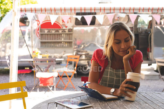 Young female waitress having coffee in outdoor cafe — Stock Photo