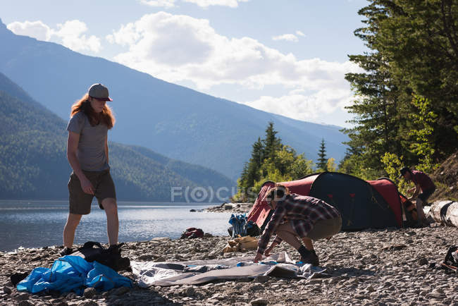 Couple setting up tent near riverside in mountains — Stock Photo
