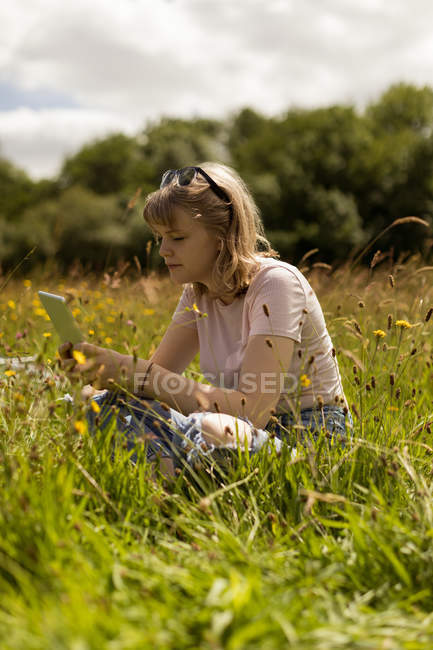 Jeune femme utilisant une tablette numérique dans le domaine — Photo de stock
