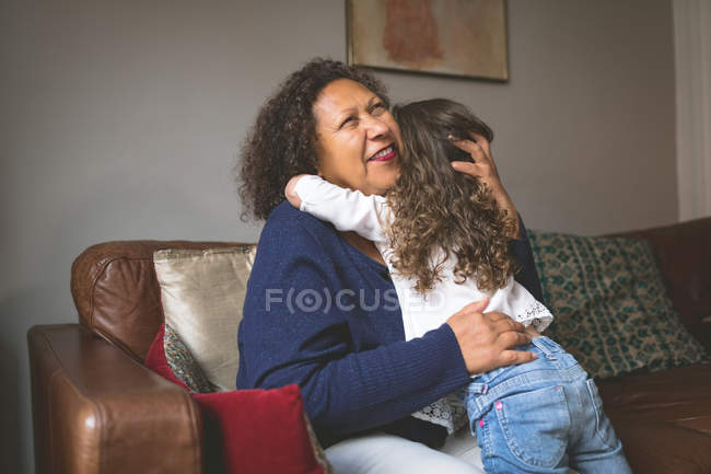 Little girl hugging grandmother at home — Stock Photo