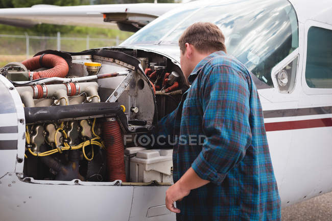 Ingenieur wartet Flugzeugtriebwerk in der Nähe des Hangars an einem sonnigen Tag — Stockfoto