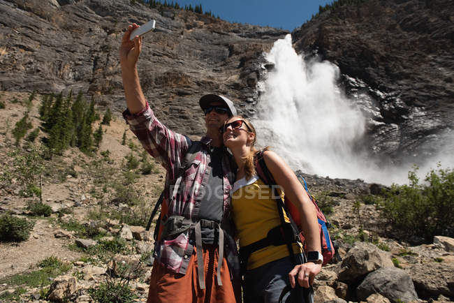 Casal tirando selfie com telefone celular nas montanhas — Fotografia de Stock